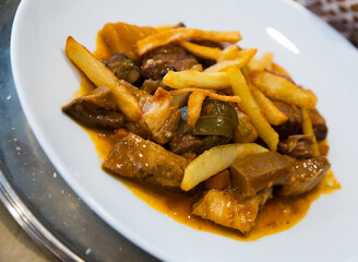 Appetizing beef stew with mushrooms and fried potatoes on white plate..