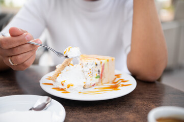 Person enjoying a slice of colorful ice cream cake with caramel drizzle