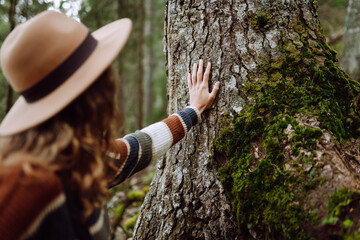 Female tourist with backpack and travel equipment touching tree while standing in the forest. Concept to love nature and tree . Environment ecology and Earth Day concept.
