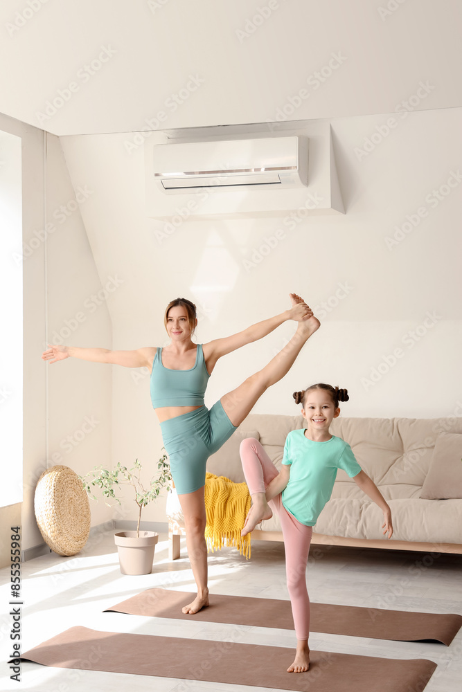 Poster Cute little girl with her mother doing yoga on mats at home