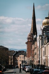 A street view of Glasgow with a church steeple and other historic buildings under a clear sky