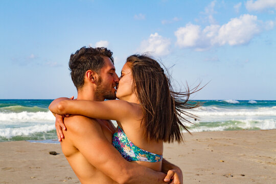 Young couple embracing and kissing at the beach in late summer at dusk