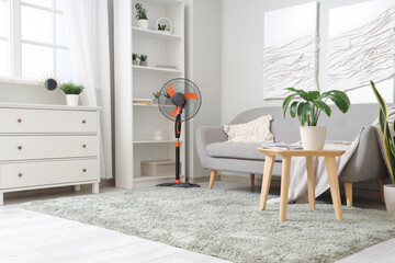 Interior of light living room with cozy grey sofa and modern floor fan