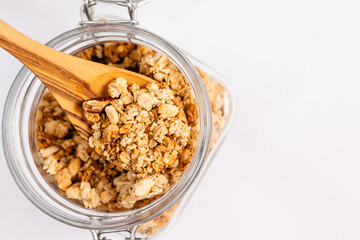 Granola in a wooden spoon from the jar close-up