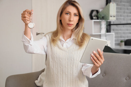 Female hypnotist with pocket watch and tablet computer in office