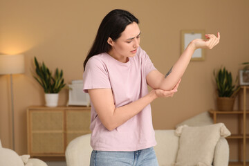 Young woman suffering from pain in elbow at home