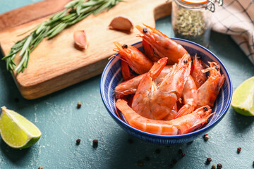 Bowl with tasty boiled shrimps and different spices on green background