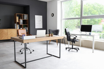 Interior of modern office with desks and shelf unit
