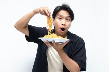 young asian man barehanded pinching fried instant noodles into his mouth. attractive asian man demonstrating how tasty the noodles are.