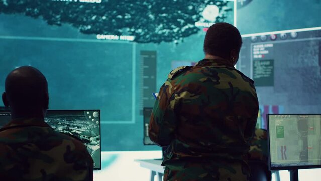Woman colonel handling a special operation with big data in monitoring room, providing important satellite information to her crew in command post. Targeting enemy power base. Camera A.