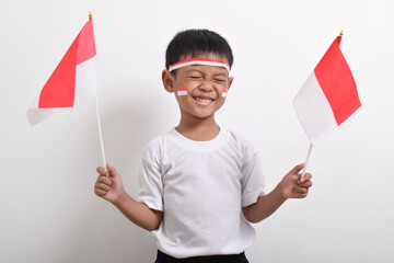 Cute little Asian boy holding Indonesia's flag to celebrate Indonesia Independence Day on August 17 isolated on white background.