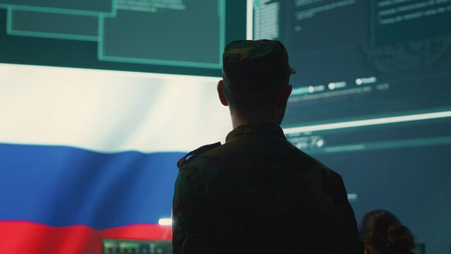 Military hacker from Russian army working in governmental control room cracking rival states network systems to spread fake news and hybrid war propaganda. Brainwashing ideology strategy. Camera A.
