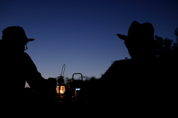 Obraz premium 夕暮れのキャンプを楽しむシルエットの男性二人