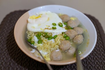 instant noodles with meat ball, egg,  chili and vegetable, in a white bowl, in the table, instant food.