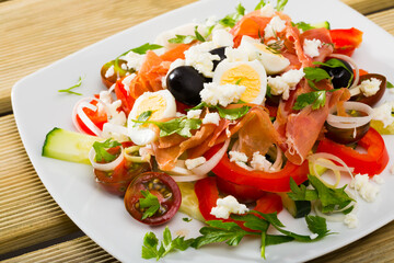 Traditional dish of Bulgarian cuisine shepherd's salad with fresh vegetables, salmon and quail eggs