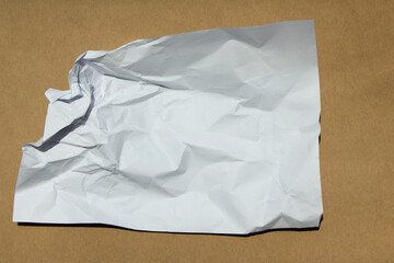 Obraz premium Crumpled paper lying on a brown background.