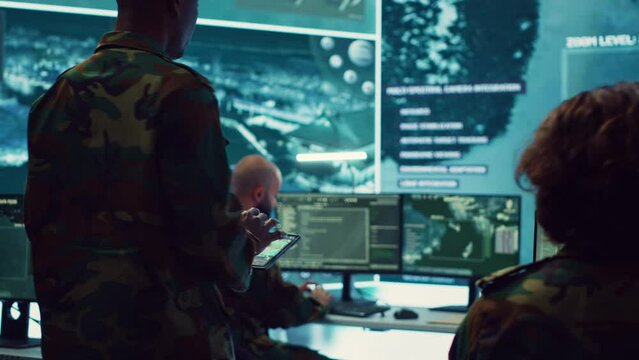 General of the army overseeing special reconnaissance mission in control center, undertake intelligence gathering operations with CCTV footage and a world map on a big screen. Camera A.