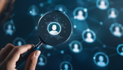 A hand holds a magnifying glass focused on a single person icon amongst a field of icons.