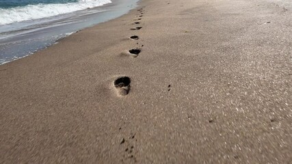 A video showcasing footprints in the sand on a beautiful sunny day at the beach.