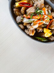 Sweet and sour sauce mushroom with chopped pepper and pineapple in a hot plate on table background.