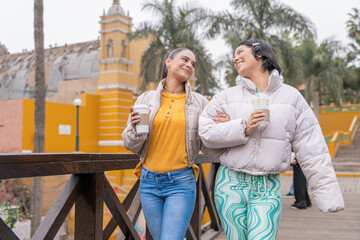 Naklejka premium Friends chatting and enjoying warm coffee exploring city in winter