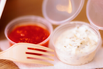 Detail of a Plastic Fork Next to Red and White Sauces. Delicious dipping Sauces from a fast food restaurant
