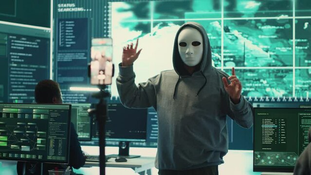 Governmental anonymous hackers group asking ransom for state secrets, important hacking activity during hybrid war. Recording a video after stealing top secret information, big screen. Camera A.