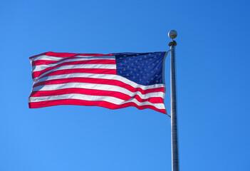 waving USA flag on pole against blue sky