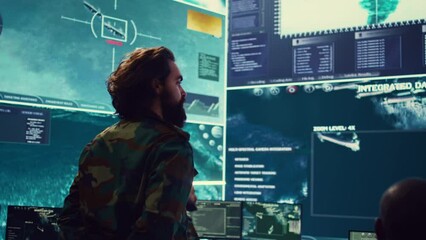 Colonel overseeing special operation to gather intelligence in control center with CCTV surveillance information on a big screen. Specialist targeting enemy military power base. Camera B.