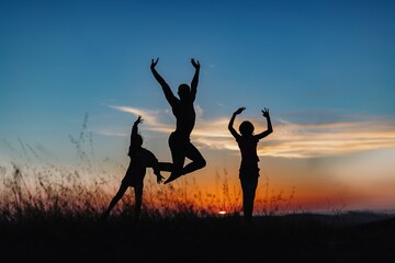 Silhouette of male ballet dancer and two children jumping and doing a majestic jump for joy in nature, Behind them are heavenly clouds and the sun is setting.