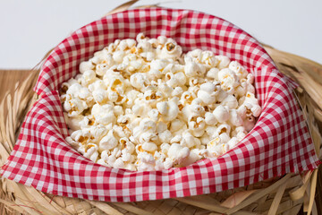 Straw bowl with red and white checkered fabric and popcorn inside. Typical food for the São João June festival.