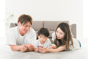 家のリビングでスマホを見る笑顔の日本人家族（動画・ファミリー）
