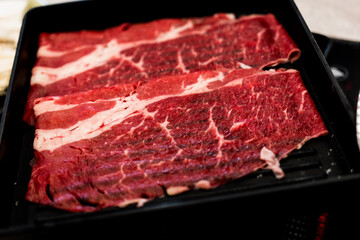 Premium rare slices of beef on a black tray plate served for hot pots and Shabu