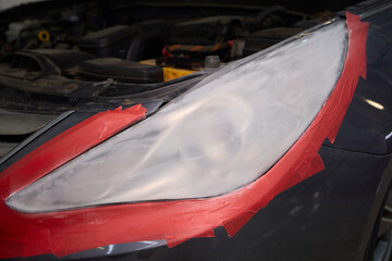 A man repaints a scratch on a car part in an auto repair shop with precision and craftsmanship