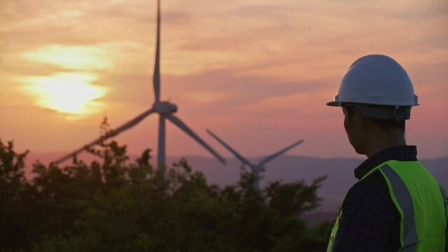 An engineer working on the mountain with huge wind turbine power generator, clean energy to net zero prevent climate change