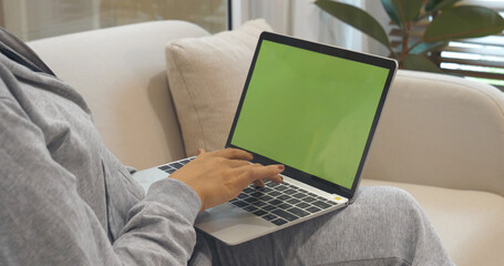 Fototapeta premium Empty Screen laptop Blogger Woman hands typing computer keyboard. Close up women hands using laptop sitting at sofa in living room. Freelance girl work from home office via internet call conference