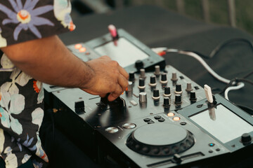 Close-up of the hands of a dj in a Hawaiian shirt playing the mixer at a summer party