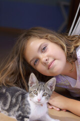 beautiful little girl lying on the floor with her little cat smiling at the camera