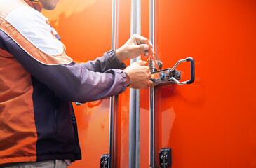 Delivery man uses a strap seal to lock a shipping container. Container door locked with protective...