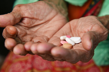 close up of pills and capsule on senior women's hand