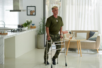 Soldier in uniform waling with walker during rehabilitation at home