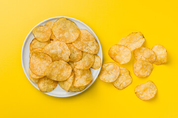 Crispy Potato Chips on plate on Yellow Background. Top view.