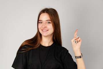 Smiling Young Woman Pointing to Copy Space Against a Grey Background