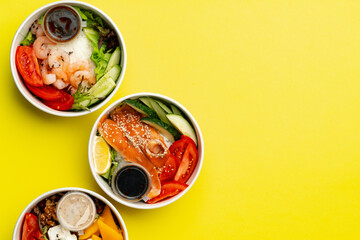 Top view of fresh poke bowls on yellow background
