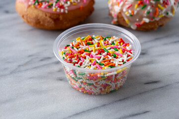 A view of a plastic condiment cup of rainbow sprinkles.
