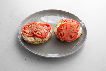 A view of a bagel with tomato, cream cheese and lemon pepper.
