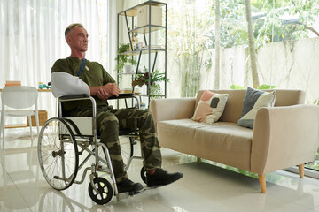 Soldier with wounded arm sitting in wheelchair during rehabilitation at home