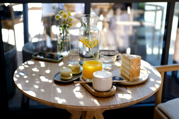 Delicious breakfast for two at the luxury hotel with fresh orange juice, vegan cake, coffee cappuccino on wooden table. Cafe brunch. Top view.