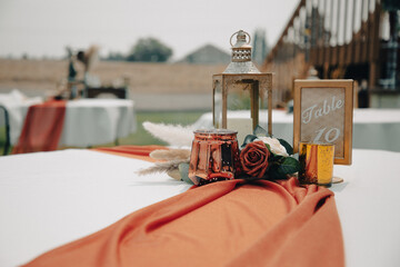 Outdoor wedding table with centerpiece of lantern, flowers, and