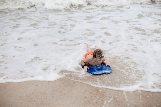 Boy riding a boogie board on the beach in Alabama